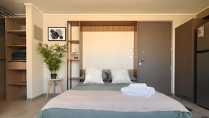 Ein modernes Schlafzimmer mit einem großen Bett, einer Zimmerpflanze und einem Kleiderschrank.