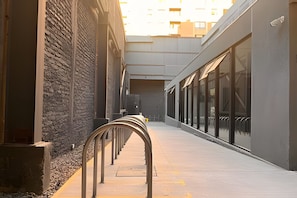 A narrow corridor with a metal railing, a stone wall on one side, and a glass building on the other. - Oceana Suites Carmen (Santiago)