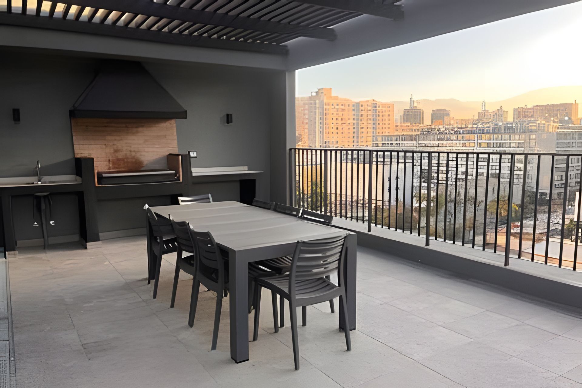 A modern outdoor dining area with a large table and chairs, a built-in grill, and a view of a cityscape.