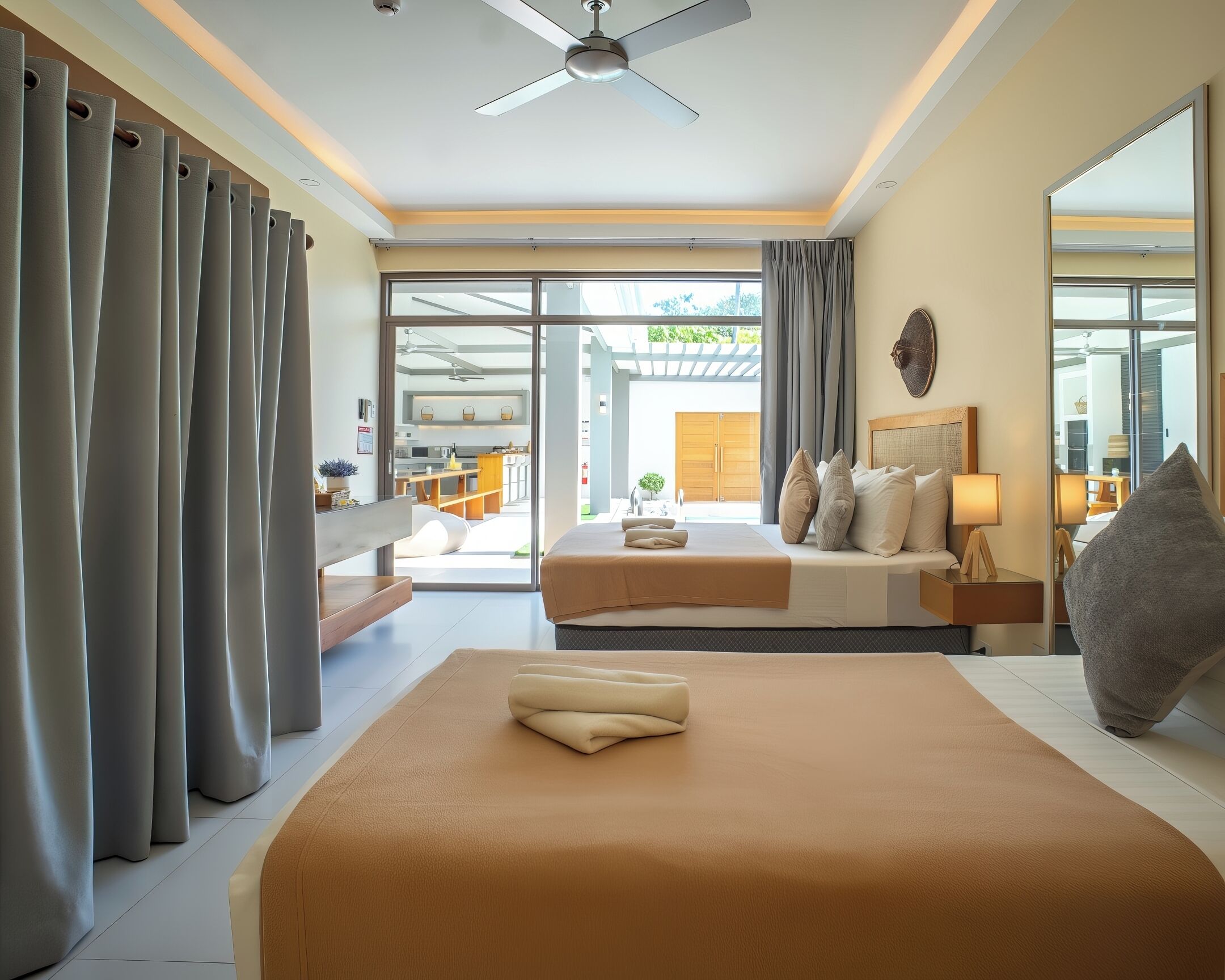Habitación de hotel con dos camas, ventilador de techo, ventana grande y vistas al exterior.