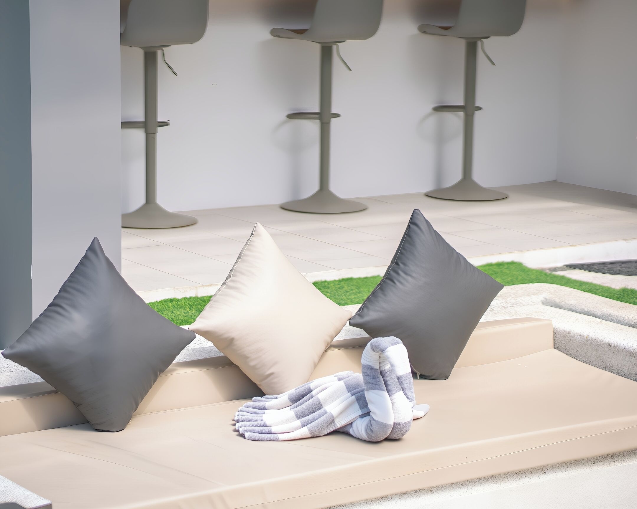 A modern lounge area with a sofa, three dark pillows, and a striped blanket.