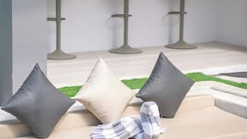 A modern lounge area with a sofa, three dark pillows, and a striped blanket.