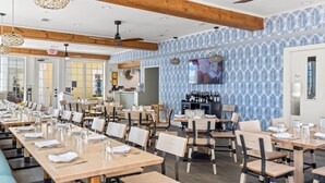 Een restaurant met lange houten tafels en stoelen, een bar en een wand met een patroon.