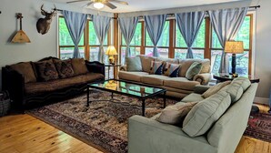 Ein Wohnzimmer mit zwei Sofas, einem Couchtisch, einem Deckenventilator und einem aufgehängten Hirschkopf.