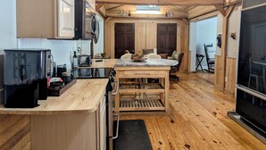Eine kompakte Küche mit Holzbalken, einer zentralen Kochinsel und einem Essbereich mit Tisch und Stühlen.