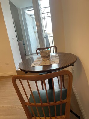 A dining area with a round table, a woven basket, and a chair with a cushioned seat.