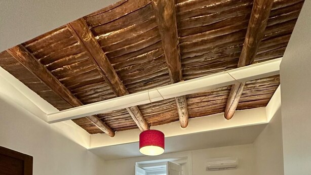 A bedroom with a wooden ceiling, a bed, a red chair, a TV, and a window. - La Romantique Napoli, 2 minutes from the largest square in Naples (Napoli)