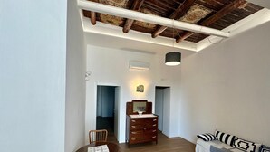 A compact living space with a dining area, a sofa, a wooden dresser, and a ceiling with exposed beams. - La Romantique Napoli, 2 minutes from the largest square in Naples (Napoli)