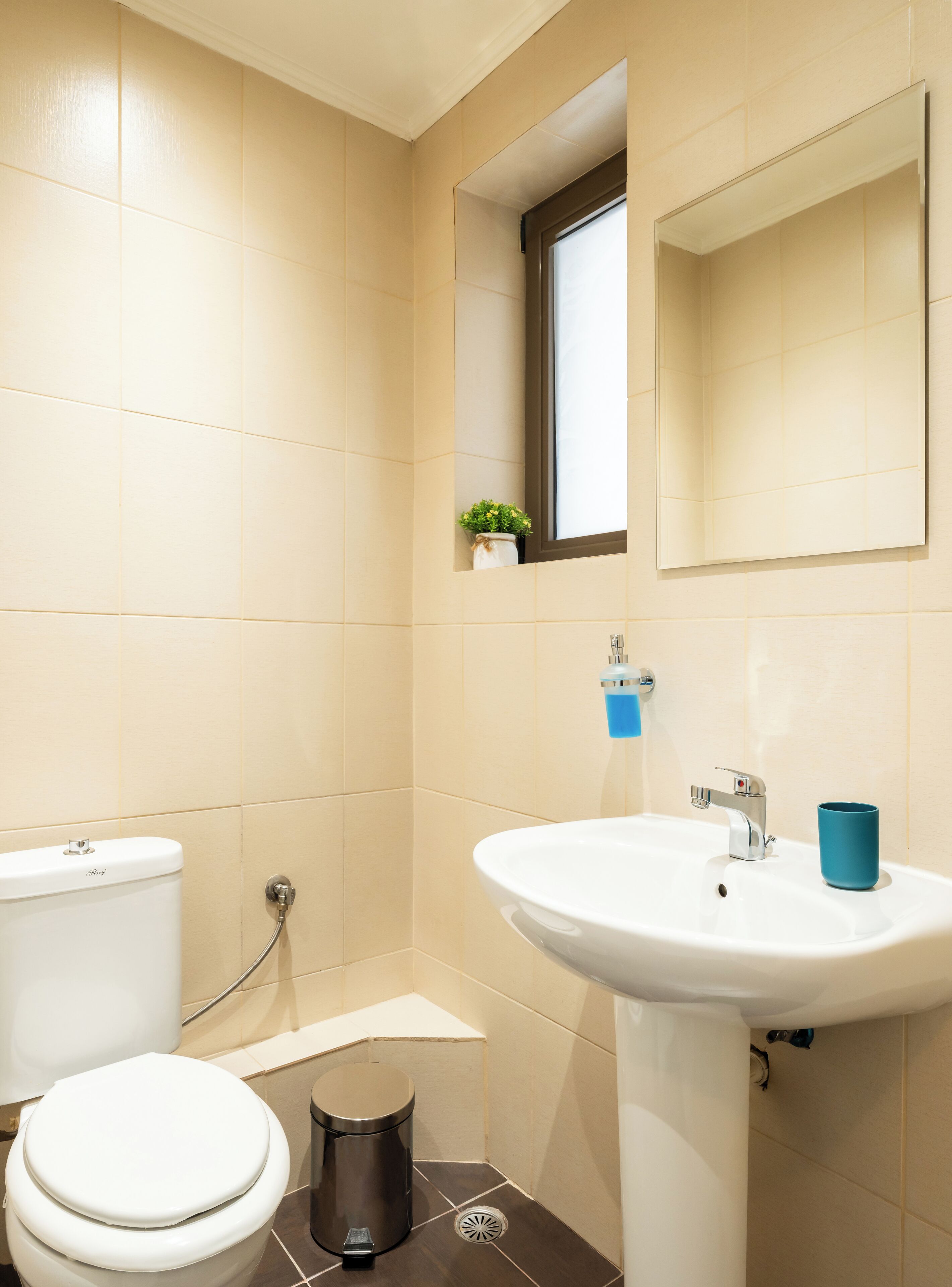 A bathroom with a toilet, sink, and mirror.