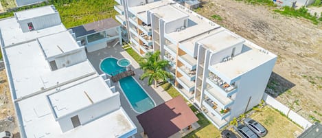 A multi-story residential building with a rooftop pool, balconies, and a small garden area.