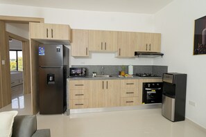 Une cuisine moderne avec des meubles en bois clair, des appareils en acier inoxydable et un plan de travail en granit.