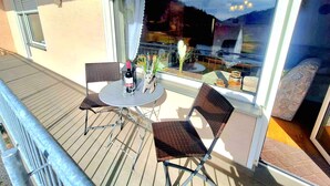 A balcony with a table, two chairs, a bottle of wine, and a vase with flowers. - Charming, family-friendly vacation apartment in the heart of the Volcanic Eifel (Niederstadtfeld)