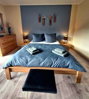 Une chambre à coucher avec un grand lit, deux tables de chevet, une commode en bois et un banc.