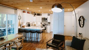 Una cocina moderna con armarios blancos, una isla central y un comedor con sillas y mesa de madera.