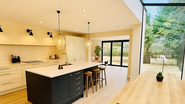 A modern kitchen with a central island, bar stools, and a dining table with a unique black base. - Stunning 5 bed house in enviable location (Bath)