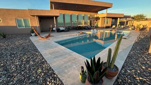 A modern house with a swimming pool, outdoor seating, and potted plants.