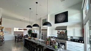 A modern kitchen with a central island, bar stools, pendant lighting, and stainless steel appliances.