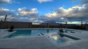 A swimming pool with a view of mountains and a cloudy sky.