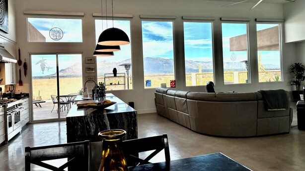 A spacious kitchen with a large island, a dining area with a table and chairs, a built-in seating area with a sofa, and large windows offering a view of the mountains.