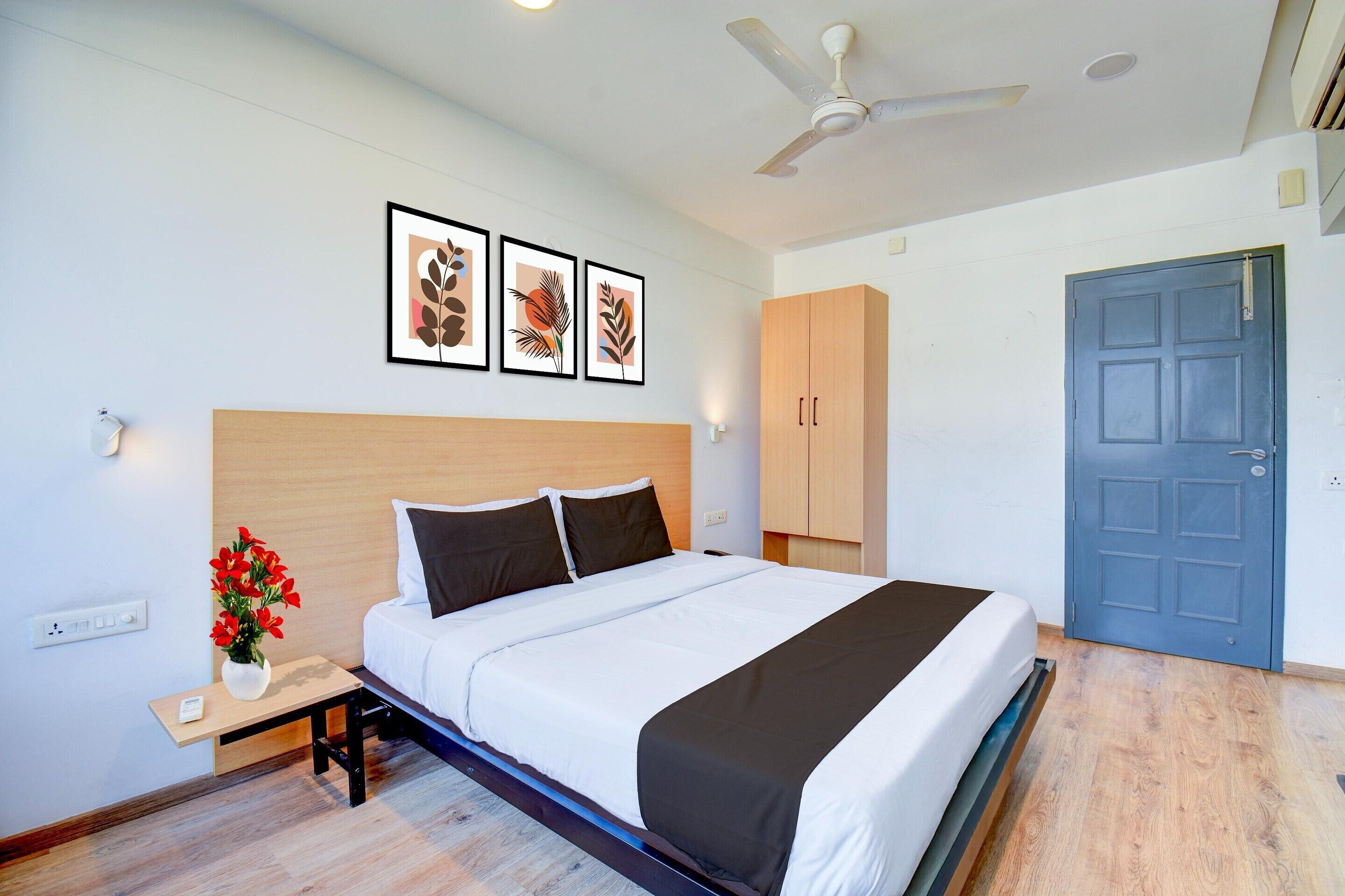 A neatly arranged bedroom with a bed, bedside table, and a vase of flowers.