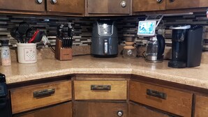 A kitchen with wooden cabinets, a coffee maker, a kettle, and various utensils. - Waterfront Home on Chadakoin River! 10 minutes to Chautauqua Lake! (Jamestown)