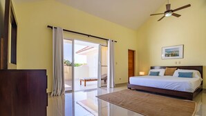 A bedroom with a bed, a ceiling fan, a large window with curtains, and a view of an outdoor patio. - Pro Cab Paradise Condos Cabarete (Cabarete)