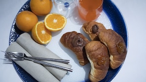 Une assiette avec des croissants, des oranges et un verre de thé.