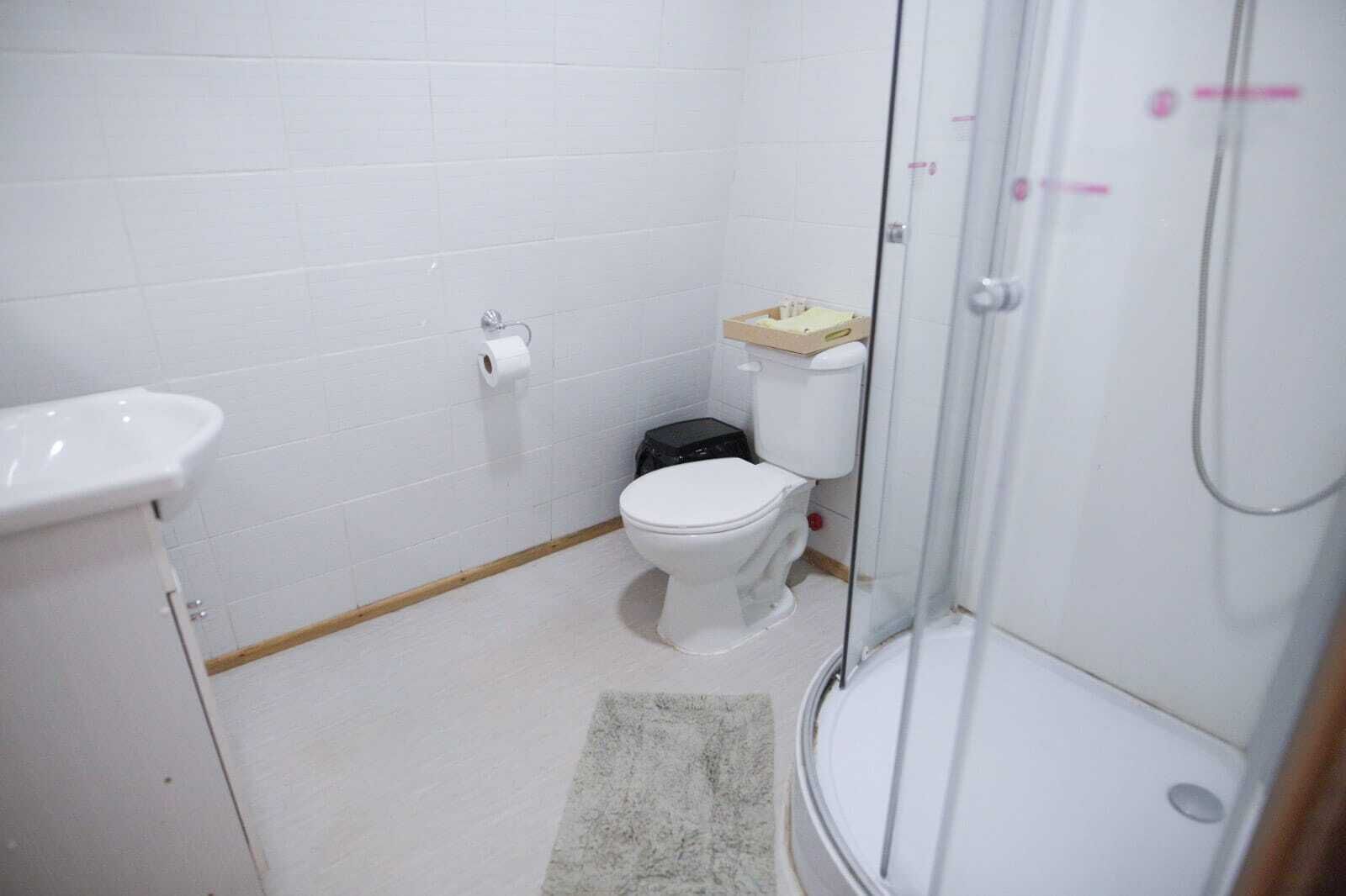 Un baño pequeño y limpio con inodoro, lavamanos y ducha.