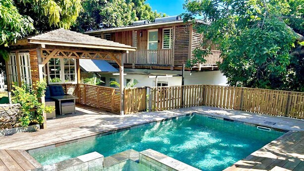 A backyard with a swimming pool, wooden deck, and a covered seating area. - Cannelle, Sea View, shared pool Mont Vert Les Bas (Montvert)