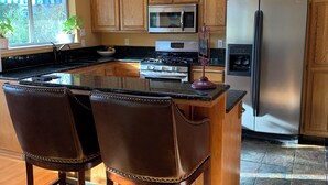 A modern kitchen with wooden cabinets, stainless steel appliances, and a central island with bar stools.
