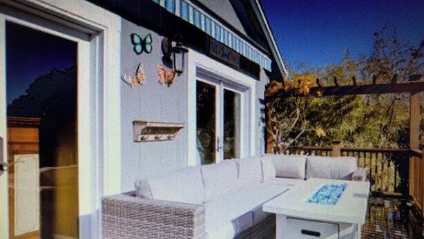 A modern house with a covered outdoor seating area, a large window, and a door.