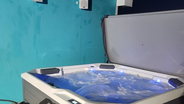 Un jacuzzi con panel de control digital, frente a una pared turquesa.