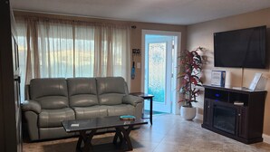 Una sala de estar con sofá, mesa de centro, televisor y chimenea.