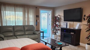 Una sala de estar con sofá, cama, mesa de centro, televisor y chimenea.