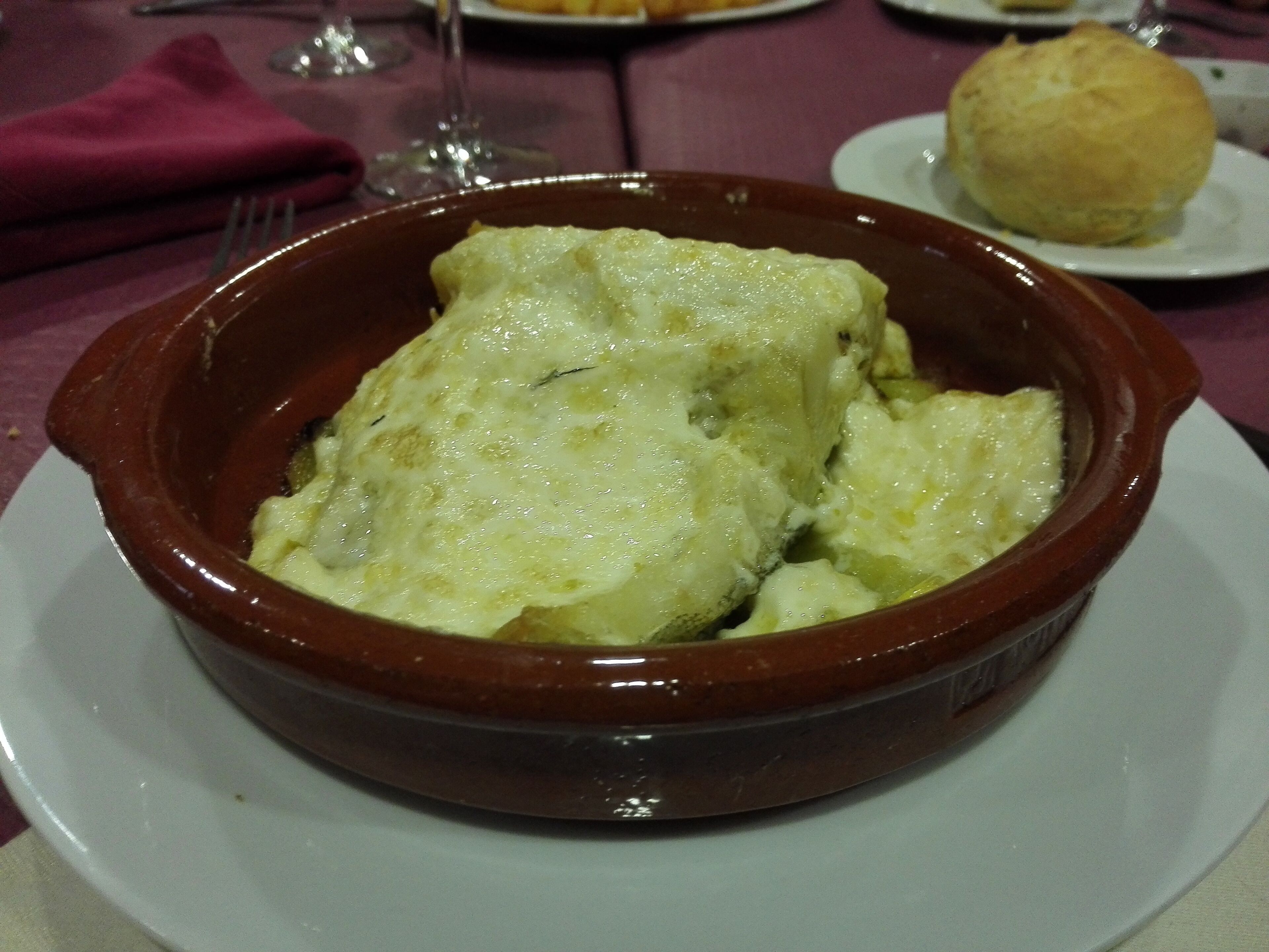 A ceramic dish with a baked dish, possibly lasagna, on a white plate.