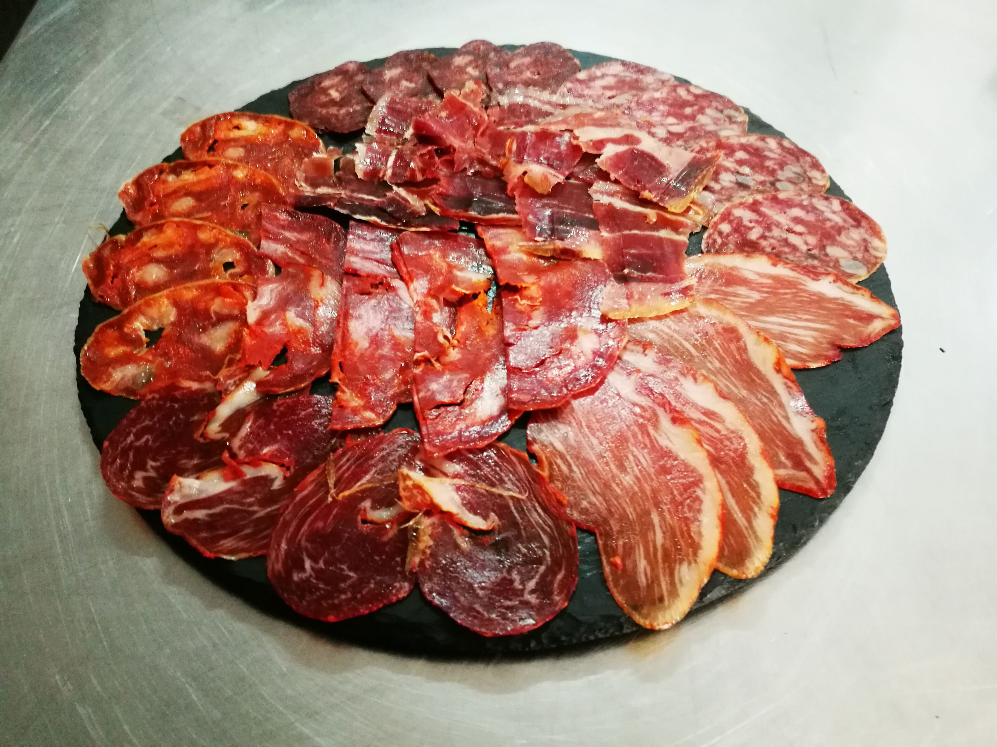 A variety of cured meats arranged on a slate plate.