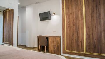 Un dormitorio con cama, escritorio, silla y televisor montado en la pared.