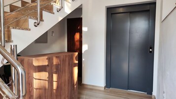 Una escalera con barandilla de madera y una puerta oscura.