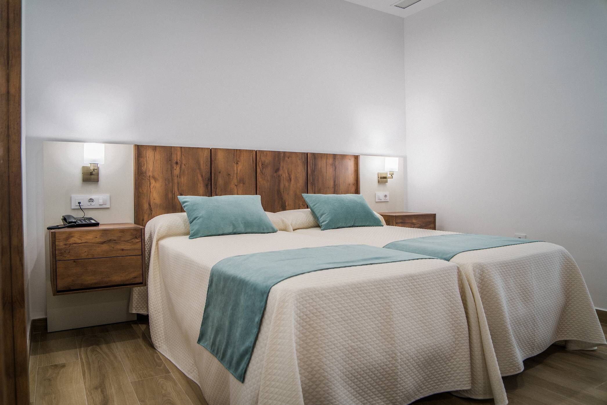 A double bed with a wooden headboard, two bedside tables, and a bedside lamp.