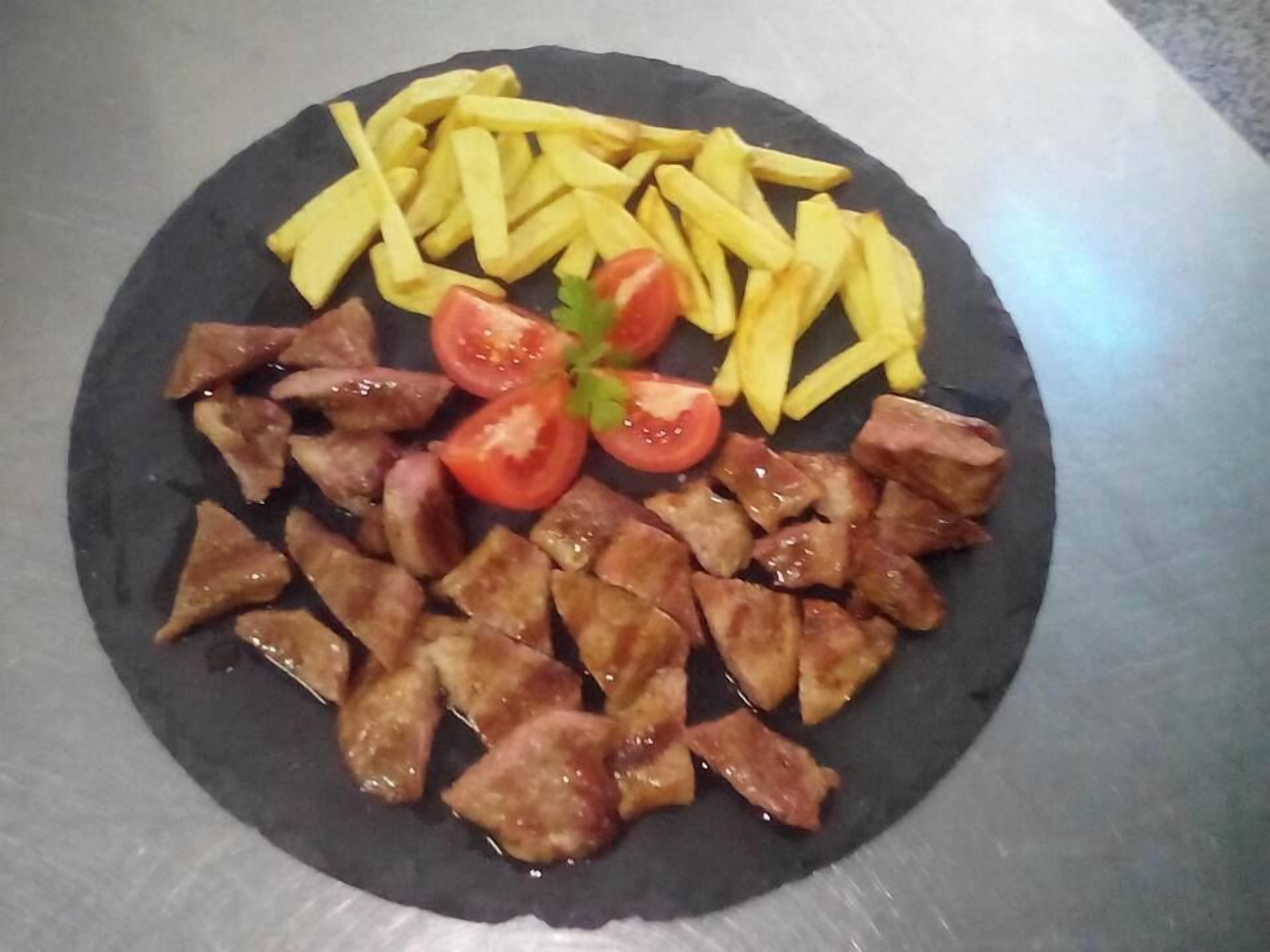 A plate with fried potatoes, grilled meat, and fresh tomato slices.