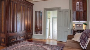 A spacious living room with a large wooden cabinet, a patterned rug, and a light blue door leading to another room. - Rustic Charm / King Bed + Roku / Private Bath (Shamokin)