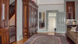 A spacious living room with a large wooden cabinet, a patterned rug, and a beige sofa. - Rustic Charm / King Bed + Roku / Private Bath (Shamokin)