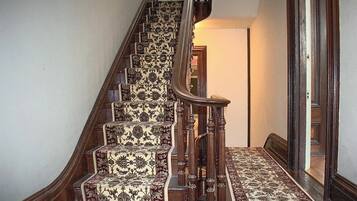 A wooden staircase with ornate carpeted steps and a handrail.