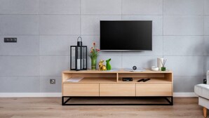Uma sala de estar moderna com um aparador de madeira, uma TV de tela plana na parede e um design minimalista.