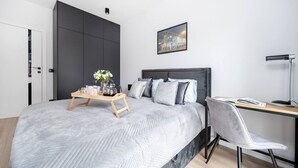 Um quarto moderno com uma cama grande, uma escrivaninha e uma cadeira.