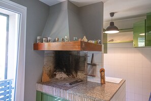 A kitchen with a built-in wood stove, a hanging light fixture, and a shelf with various kitchen items. - Bea&Berto - B&B (Pesaro)