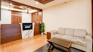 A reception area with a wooden reception desk, a sofa, a coffee table, and a potted plant.
