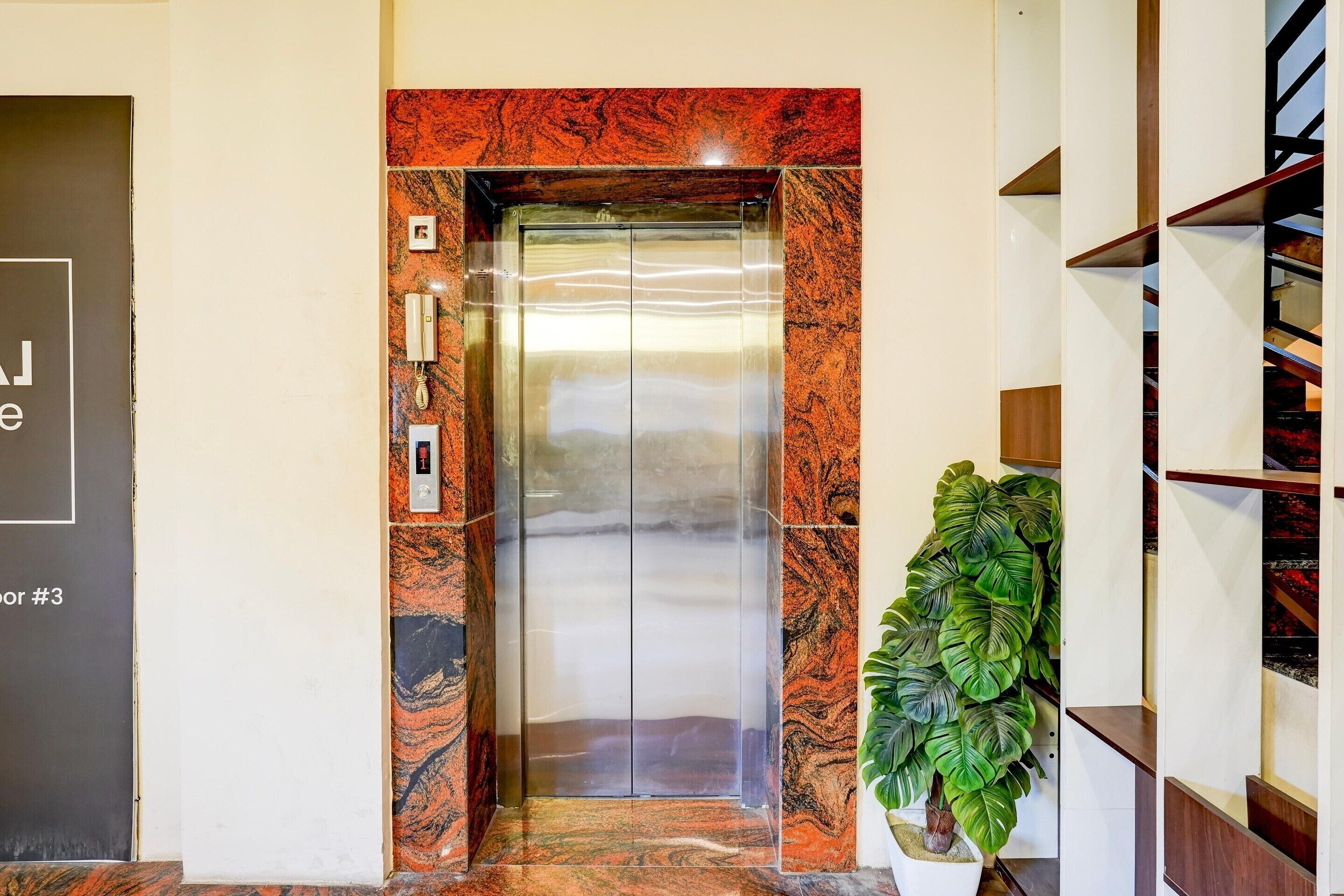 An elevator with a marble wall, a potted plant, and a sign indicating "Floor #3".