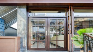 A hotel entrance with a glass door, a staircase, and a potted plant.