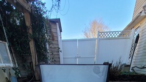 Un bain à remous avec un banc en bois devant, entouré d’une terrasse en briques et d’une clôture en bois.